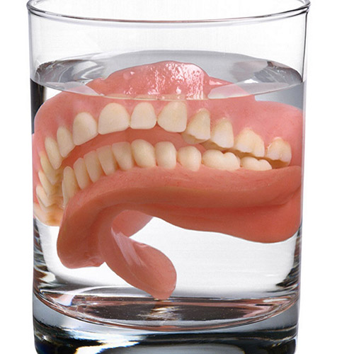 Dentures soaking in a glass.